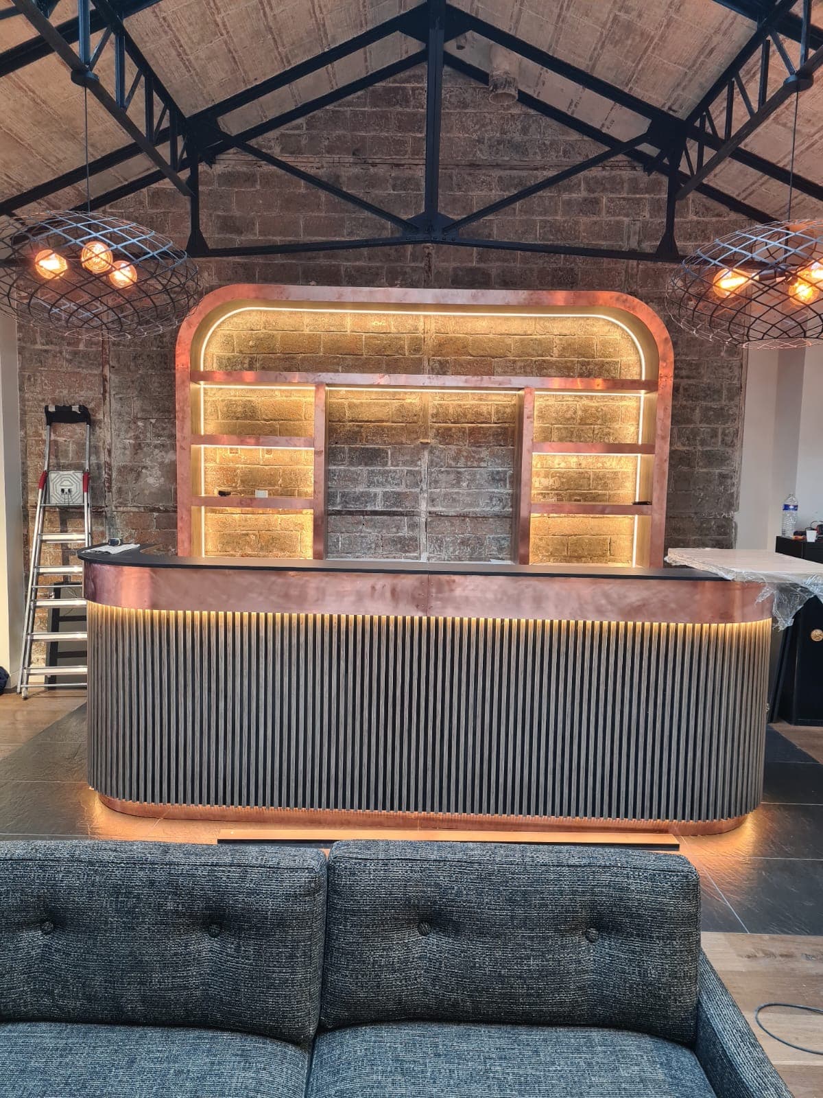 Bar de restaurant sur mesure en cuivre patiné et bois cannelé réalisé par Pro Batiment