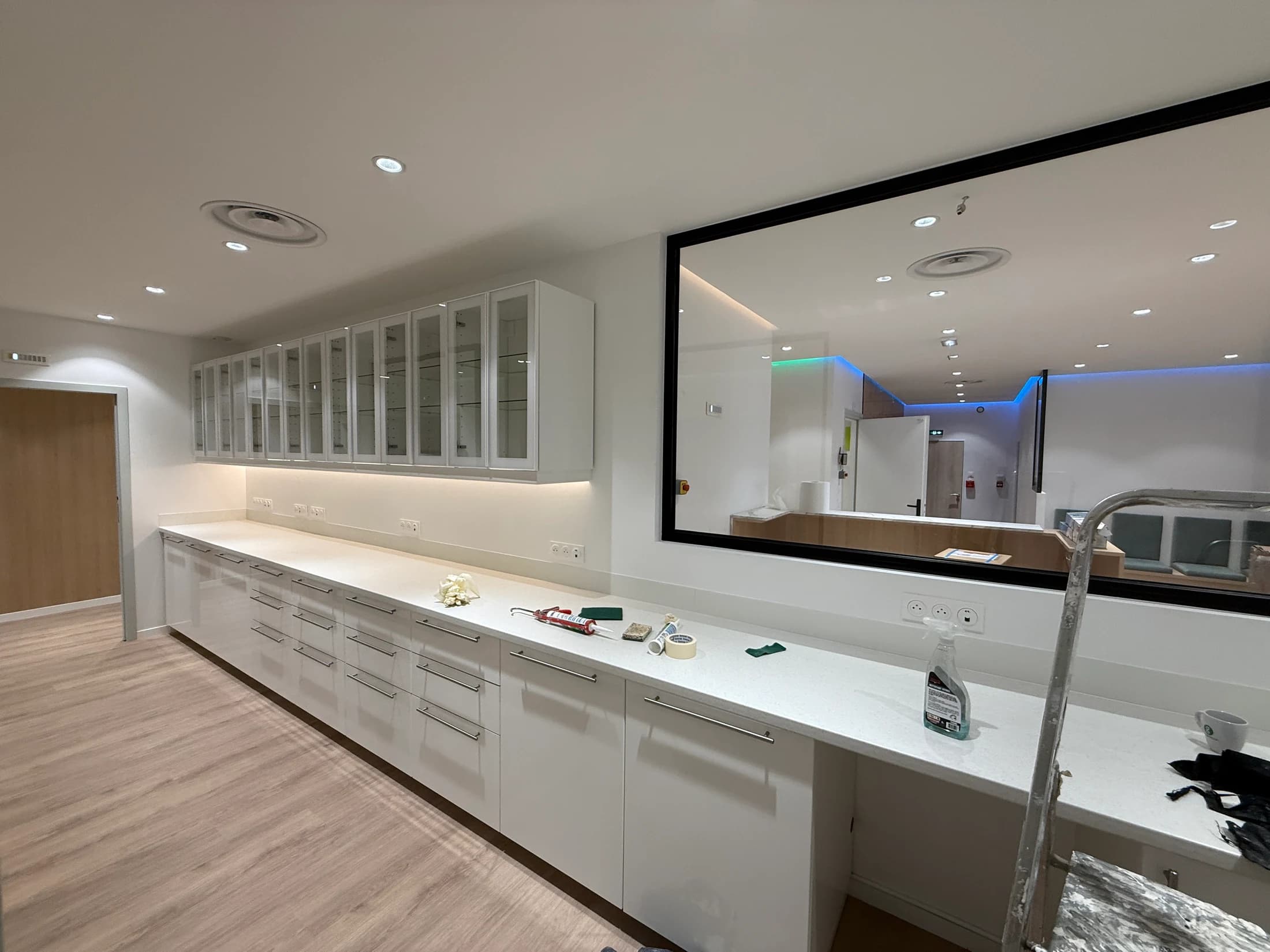 Mobilier technique blanc, rangements vitrés et long plan de travail en fin d’installation